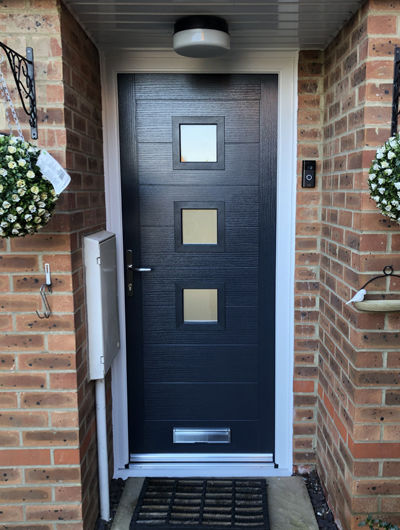 Anthracite grey Monza 3 Square composite door with a white frame in a brown brick home