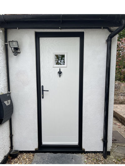 White composite door with black frame in a white walled house with black surround