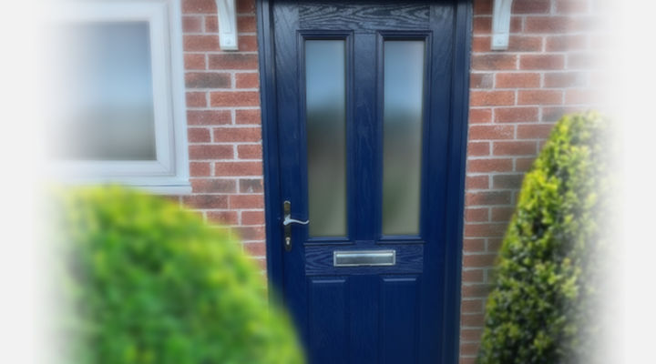 Blue composite front door within a red brick house