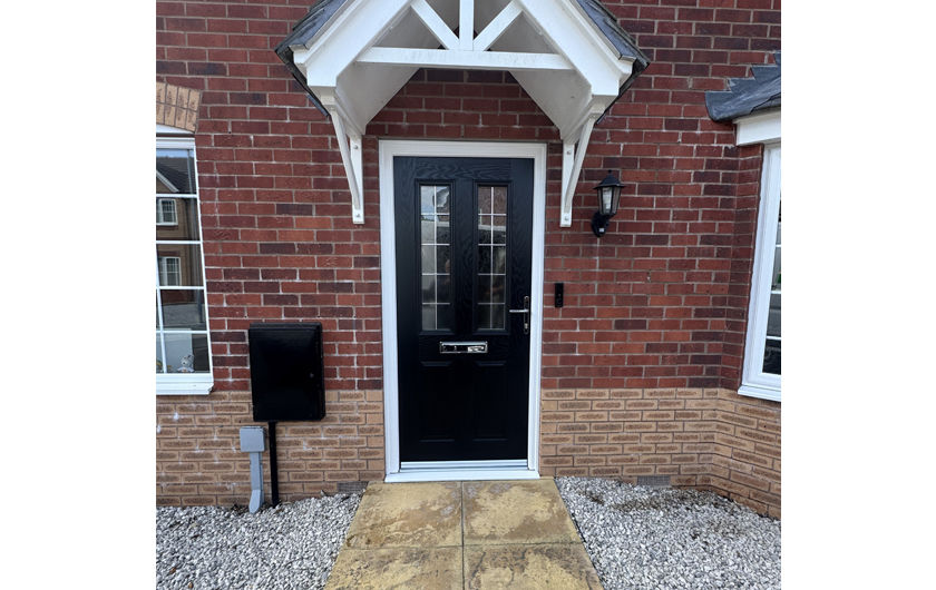 Red brick home with a black composite front door with Box Lead glass under a white arched canopy