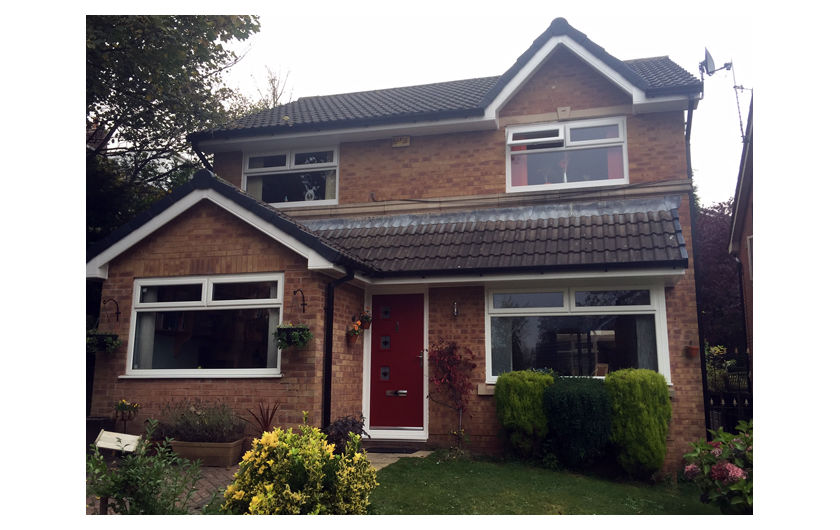 A red composite door with white frame on a house with white UPVC windows