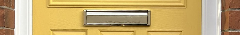 Close-up of a chrome letterplate in a yellow composite door